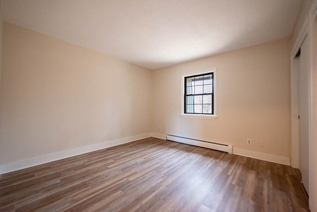 empty room featuring baseboard heating and hardwood / wood-style floors