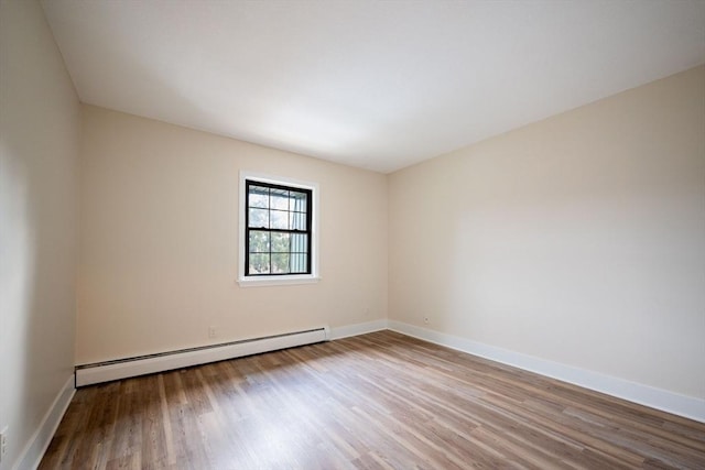 unfurnished room featuring a baseboard heating unit and light hardwood / wood-style floors