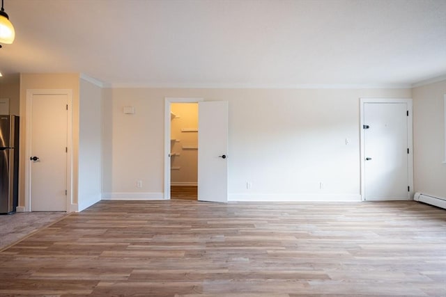 empty room with light wood-type flooring, ornamental molding, and a baseboard radiator