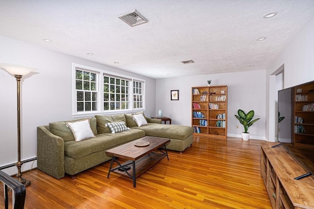 32 Eaton Rd W, Framingham, MA 01701 - living room with light wood finished floors, a baseboard radiator, a textured ceiling, and recessed lighting