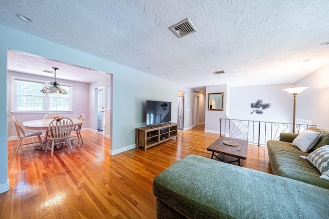 32 Eaton Rd W, Framingham, MA 01701 - living room with a textured ceiling, light wood-style flooring, and a chandelier