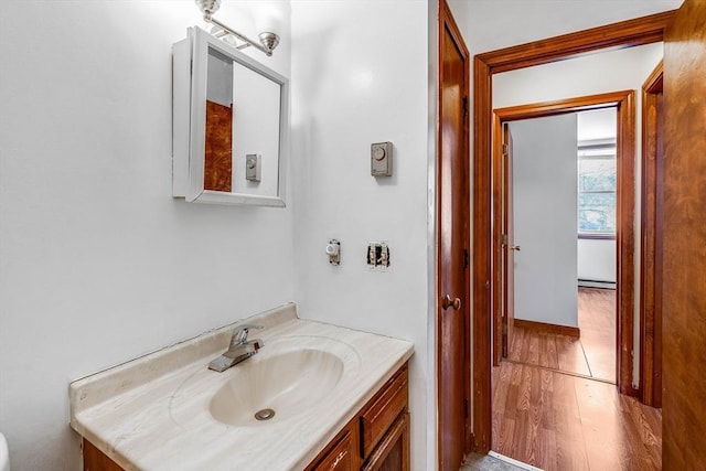 bathroom with vanity, hardwood / wood-style floors, and a baseboard heating unit