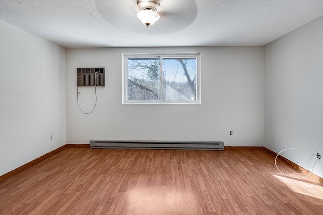 empty room featuring baseboard heating, light hardwood / wood-style floors, and a wall unit AC