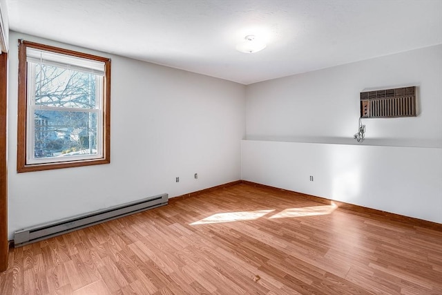 empty room featuring a wall mounted AC, baseboard heating, and light hardwood / wood-style flooring