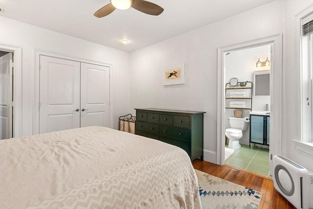 bedroom featuring hardwood / wood-style floors, heating unit, ceiling fan, a closet, and connected bathroom