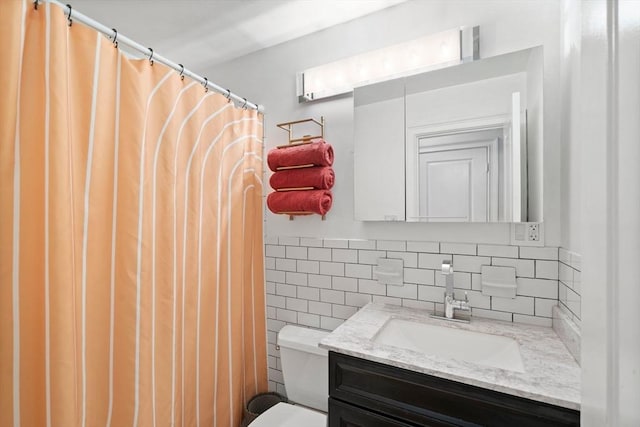 bathroom with toilet, vanity, and tile walls