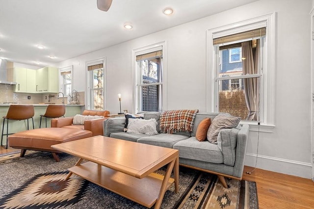 living room with light wood finished floors, recessed lighting, a healthy amount of sunlight, and baseboards