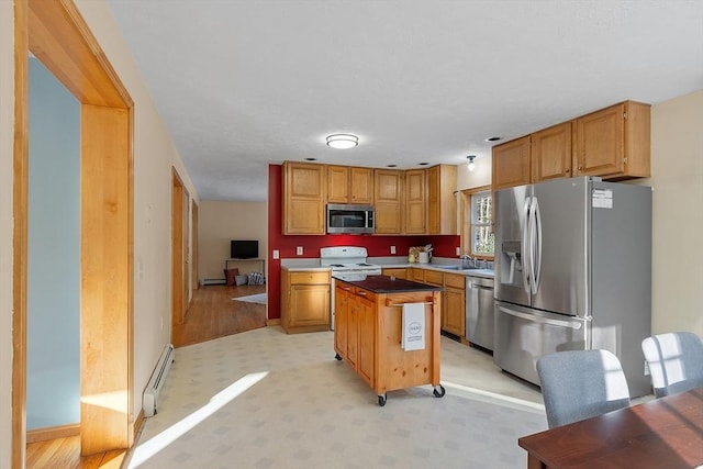 kitchen with stainless steel appliances, sink, a center island, and baseboard heating