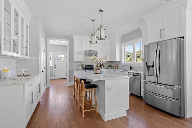 kitchen with backsplash, stainless steel appliances, sink, white cabinets, and a kitchen island