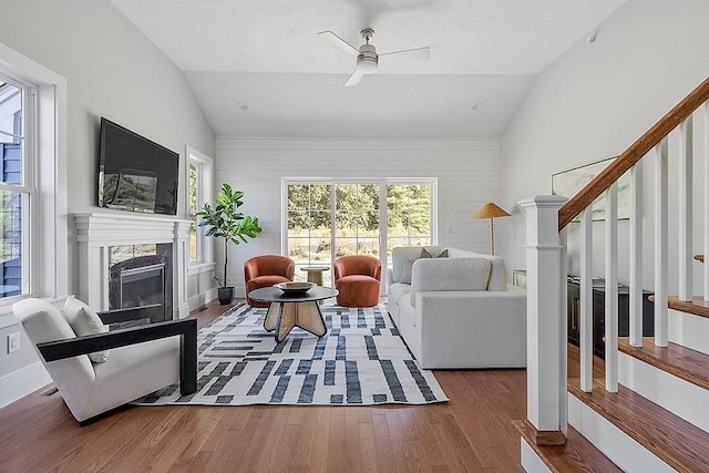 living room with a premium fireplace, ceiling fan, wood-type flooring, and vaulted ceiling