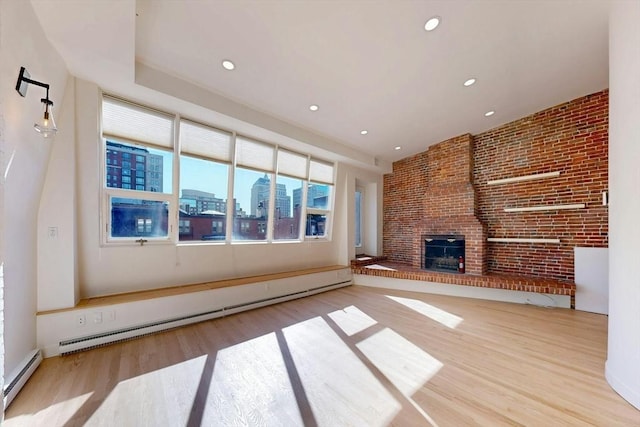 unfurnished living room with a baseboard radiator, a fireplace, a baseboard heating unit, and light wood-style flooring