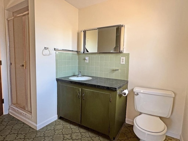 bathroom featuring toilet, backsplash, a shower stall, baseboards, and vanity