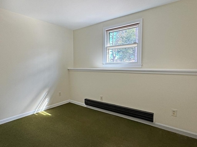 spare room with dark carpet, a baseboard heating unit, and baseboards