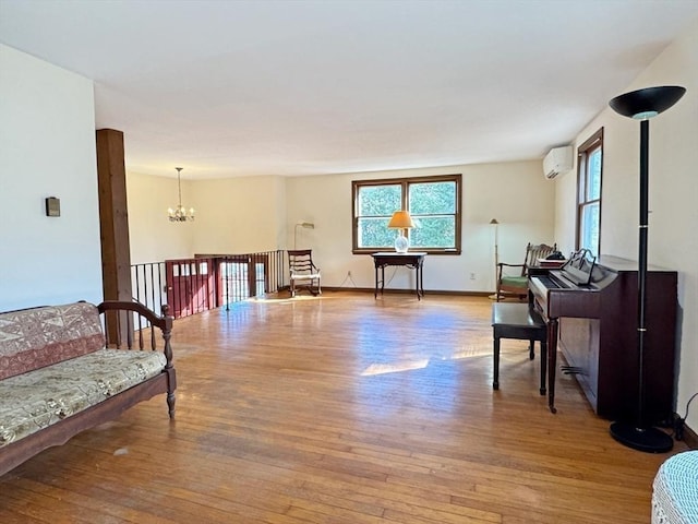 living area featuring a notable chandelier, baseboards, hardwood / wood-style flooring, and a wall unit AC