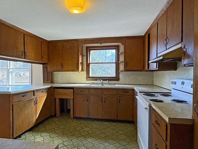 kitchen featuring white electric range, under cabinet range hood, a wealth of natural light, and light countertops