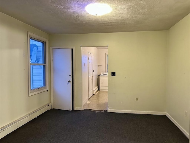 spare room with washer / clothes dryer, a baseboard heating unit, and a textured ceiling