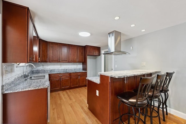 451 Lincoln St, Abington, MA 02351 - kitchen with island exhaust hood, a sink, light wood-style floors, a kitchen breakfast bar, and backsplash