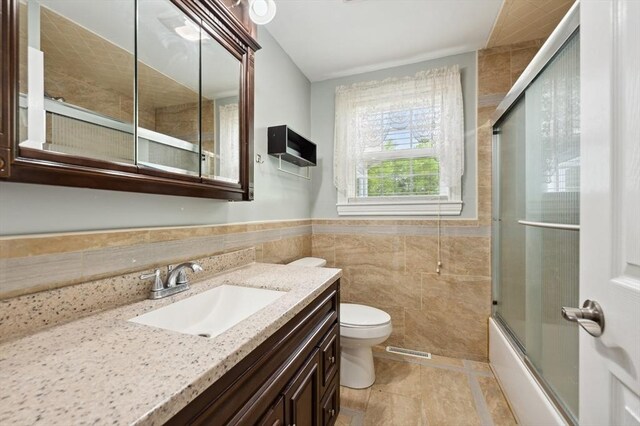 451 Lincoln St, Abington, MA 02351 - bathroom featuring tile walls, toilet, vanity, bath / shower combo with glass door, and wainscoting