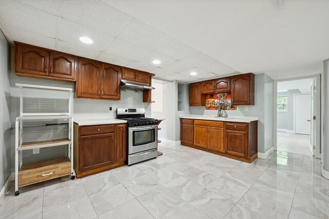 451 Lincoln St, Abington, MA 02351 - kitchen with stainless steel range with gas stovetop, under cabinet range hood, light countertops, baseboards, and a sink