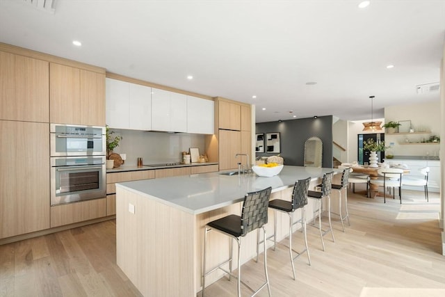 33 Conwell Ave, Somerville, MA 02144 - kitchen featuring double oven, modern cabinets, light wood-style floors, a kitchen breakfast bar, and recessed lighting