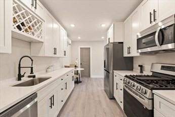 17 Webb St Unit 1, Salem, MA 01970 - kitchen with appliances with stainless steel finishes, a sink, white cabinetry, light wood-style floors, and light countertops