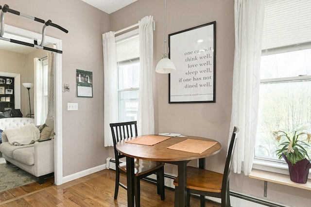 dining space featuring wood finished floors, baseboards, and a baseboard radiator