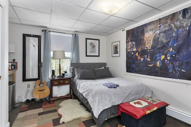 bedroom featuring a baseboard heating unit and a paneled ceiling