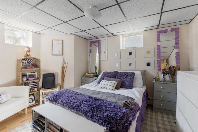 bedroom with wood finished floors and a drop ceiling