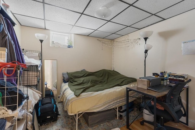 bedroom with wood finished floors and a drop ceiling