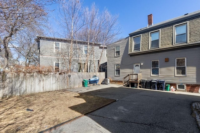 back of property with a patio area, a chimney, and fence