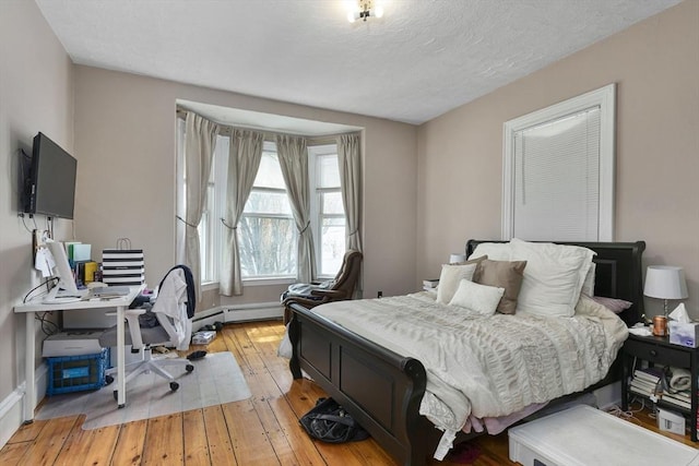 bedroom featuring baseboards, a textured ceiling, and light wood-style flooring