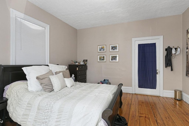 bedroom with baseboards, wood-type flooring, and a textured ceiling