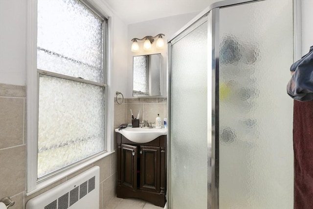 full bathroom with a stall shower, tasteful backsplash, radiator heating unit, tile walls, and vanity