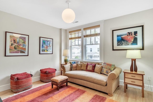 sitting room with baseboards, visible vents, and light wood-style floors