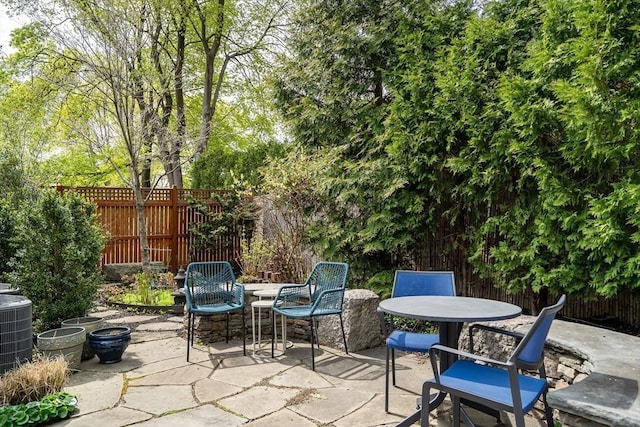 view of patio with central air condition unit, outdoor dining space, and a fenced backyard