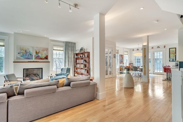 living room featuring light wood-style floors, baseboards, and a glass covered fireplace