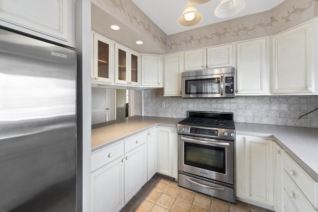 kitchen featuring glass insert cabinets, white cabinetry, stainless steel appliances, and backsplash