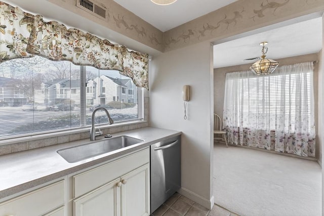 kitchen with stainless steel dishwasher, light tile patterned floors, sink, and white cabinets