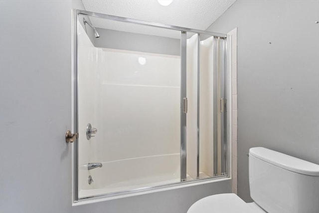 bathroom featuring toilet, shower / bath combination with glass door, and a textured ceiling