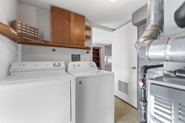 laundry room featuring washing machine and clothes dryer, visible vents, and heating unit