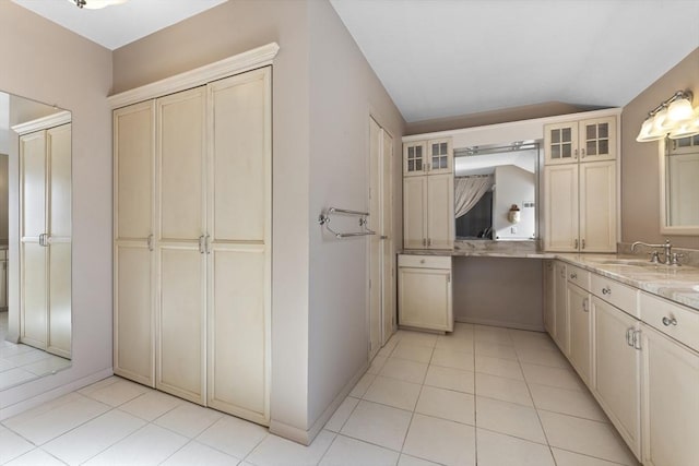 bathroom featuring lofted ceiling, vanity, baseboards, and tile patterned floors