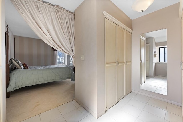 bedroom featuring light carpet, light tile patterned floors, multiple windows, and a closet