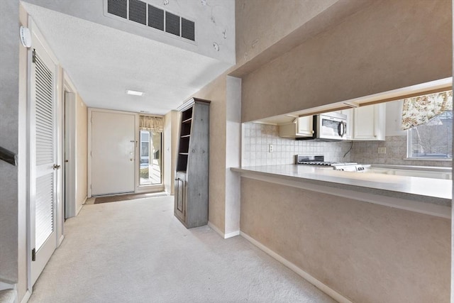 kitchen featuring light colored carpet, range, and backsplash