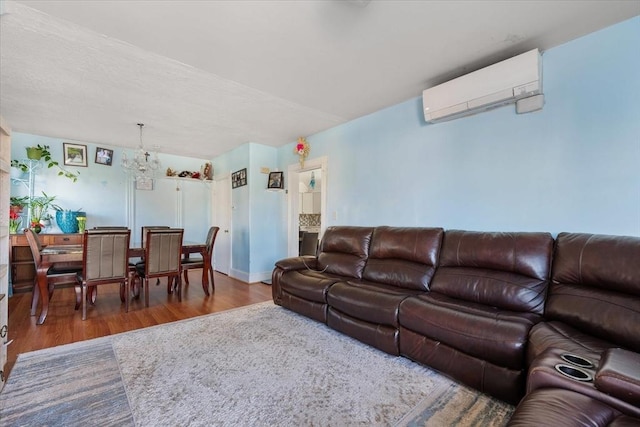 living room with a chandelier, wood-type flooring, and a wall unit AC