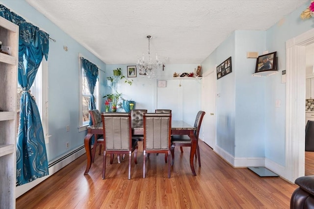 dining space featuring a notable chandelier, wood-type flooring, and a textured ceiling