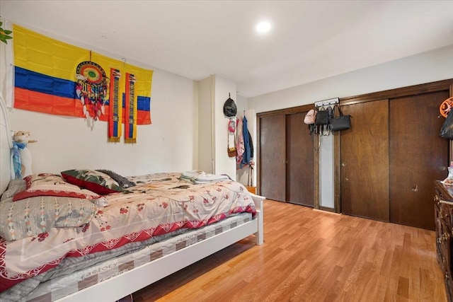 bedroom with light hardwood / wood-style flooring and two closets