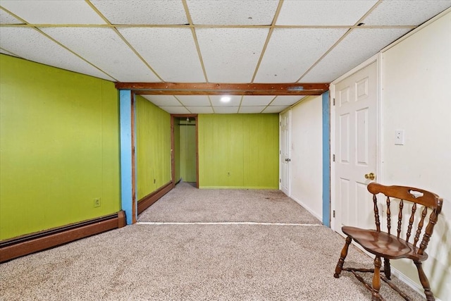 basement featuring a paneled ceiling, a baseboard radiator, and light colored carpet