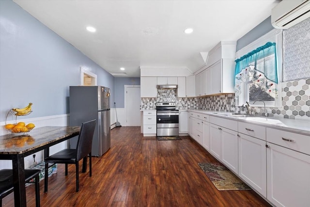 kitchen with stainless steel appliances, a wall unit AC, sink, white cabinets, and dark hardwood / wood-style floors