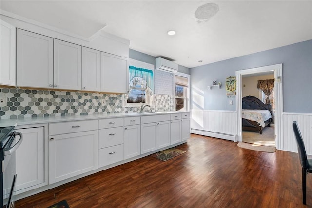 kitchen featuring a baseboard heating unit, sink, an AC wall unit, white cabinetry, and stainless steel range with electric cooktop