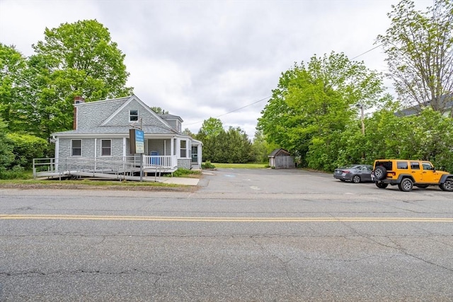 18 Main St, Templeton, MA 01468 - view of front of house featuring uncovered parking, a chimney, a storage shed, stone siding, and view of scattered trees